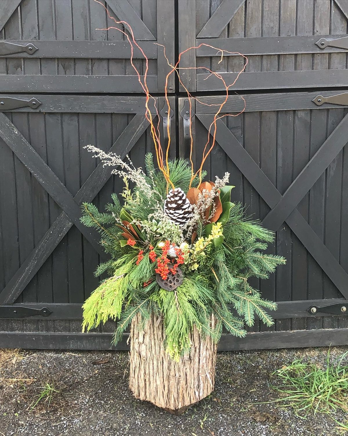 Winter urn arrangement against black barn doors